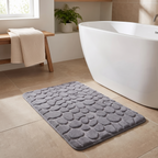Cobblestone bath mat beside a freestanding bath